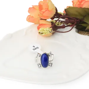 Anello vintage con zaffiro blu ovale e cristalli su un vassoio decorativo bianco