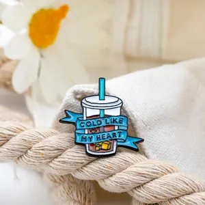 Lustige Emaille-Brosche in Kaffeetassenform mit 'Cold Like My Heart' auf Segeltuch