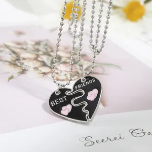 Détail du collier Best Friends avec cœur fendu en émail noir et petits cœurs roses