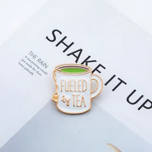 Detail of Fueled by Tea enamel pin with white mug and green tea on background