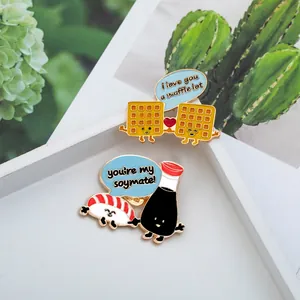 Dettaglio di pin smaltate kawaii con sushi al salmone e waffle con giochi di parole