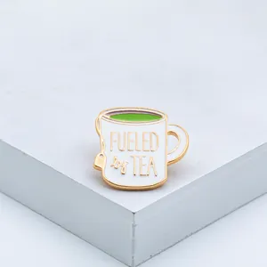 Creative tea cup enamel brooch pin featuring Fueled by Tea text and gold metal edges