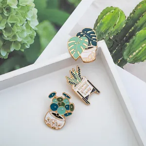 Macro shot of three botanical enamel pins including a Monstera and Crazy Plant Lady design