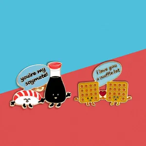 Dettaglio di spille in smalto con disegni di sushi e waffle e giochi di parole dolci