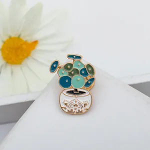 Macro detail of a potted plant enamel brooch with gold trim on a white display base