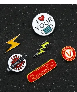 Macro shot of zinc alloy enamel pins with pandemic slogans on a black textured background