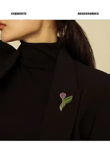 Detailed view of a purple tulip enamel brooch pinned to a professional black suit lapel