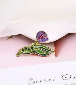 Detailed close-up of a purple tulip enamel brooch with green leaves and gold outlines