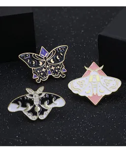 Vue détaillée de broches émaillées papillon avec motifs de lune et d'étoiles mystiques