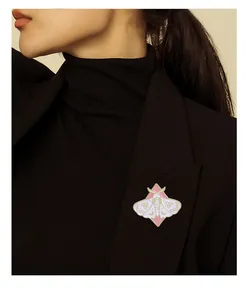 Détail du pin's émaillé papillon rose avec motif lune sur revers de veste