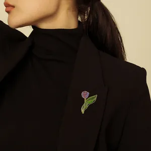 Elegant purple tulip enamel brooch with gold-tone edges pinned on a black suit lapel