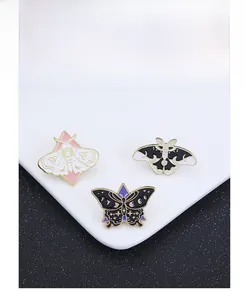 Détail des broches papillon et mite en émail avec motifs mystiques de lune et d'étoiles