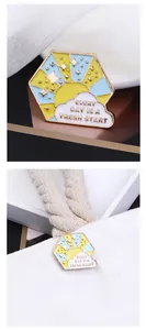 Detail of enamel pin with sun and cloud quote on a white canvas bag strap