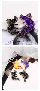 Close-up of cute axolotl enamel pins in black, purple, and yellow on a white dish