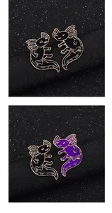 Close-up of black and purple axolotl enamel pins with gold metal trim on star texture