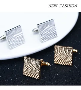 Macro detail of square cufflinks with grid texture in gold and silver finish