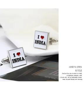Macro di gemelli quadrati in argento con scritta I love India su un piatto di ceramica