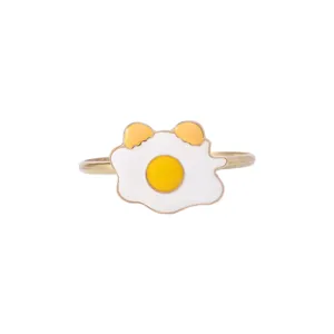 Detailed close-up of a golden napkin ring with a cute cartoon fried egg enamel design
