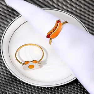 Detail showing cartoon hot dog and fried egg napkin rings on a white napkin and plate