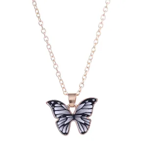Detailed close-up of a butterfly pendant with black and white patterns on a gold chain