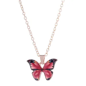 Detail showing a rose gold O-chain necklace with a gradient pink butterfly pendant