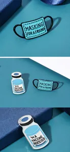 Détail des broches en émail bleu avec motifs masque et vaccin sur une boîte cadeau