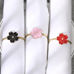 Detailed close-up of cherry blossom napkin rings in pink, red, and black enamel on white fabric