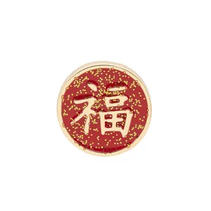 Detailed close-up of a red and gold round lucky Fu character badge with glitter finish