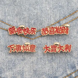 Detail of red enamel Lunar New Year brooches with gold glitter and Chinese luck characters