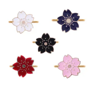 Five colored cherry blossom napkin rings with golden metal edges on white background