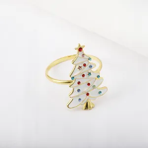Close-up of golden napkin ring with white enamel Christmas tree and colorful rhinestones