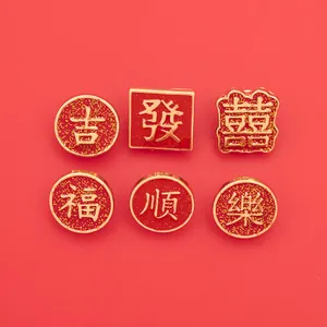 Close-up of gold Chinese character pins for Luck and Fortune with red glitter details