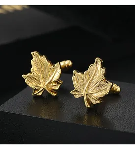 Macro detail of vintage gold maple leaf cufflinks featuring intricate vein textures