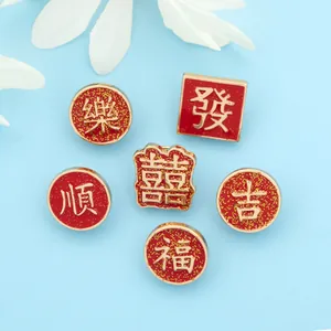 Close-up of red and gold enamel lapel pins with traditional Chinese luck characters