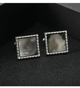 Close-up of square cufflinks with silver grooved frames and black iridescent pearl inlay