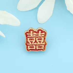 Close-up of a red enamel Xi character pendant with gold glitter and floral accents