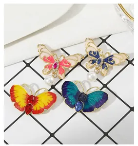 Détail de quatre broches papillon en émail avec strass et pendentifs en perles