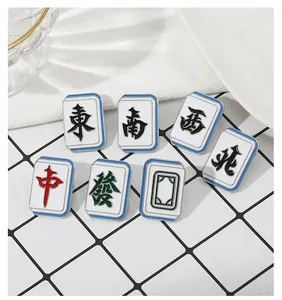 Set of seven Chinese Mahjong enamel pins arranged on a grid surface for detail view