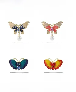 Vue détaillée de broches papillon avec émail, strass et pendentifs en perles