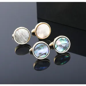 Close-up of golden cufflinks with iridescent abalone shell and white mother of pearl