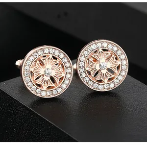 Detail of rose gold round cufflinks with white zircons on a black textured stand