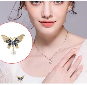 Détail d'une élégante broche papillon avec ailes en émail bleu, cristaux et perle blanche