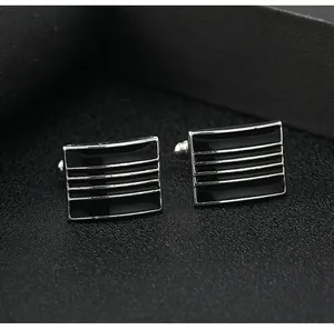 Macro detail of rectangular silver metal cufflinks with horizontal black enamel stripes