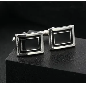 Close-up of sleek black enamel silver metal cufflinks on a textured leather display box