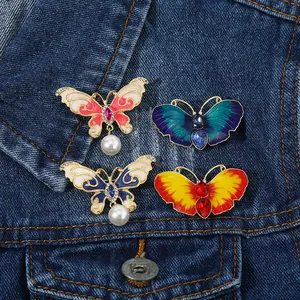 Lot de quatre broches papillon avec perles et cristaux sur tissu en denim bleu