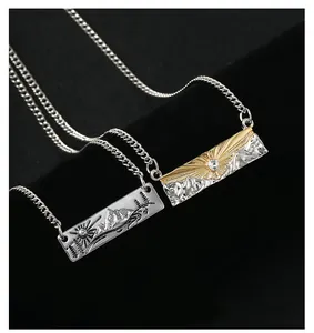 Close-up of mountain and sun pendant necklaces with diamond accents on black fabric