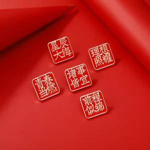 Lot de cinq broches carrées en émail rouge et or avec calligraphie chinoise
