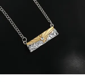 Close-up of dual-tone rectangular pendant with sun engraving and mountain relief detail