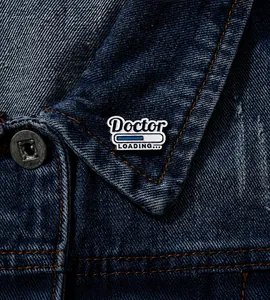 Detail shot of 'Doctor LOADING' enamel pin on a blue denim jacket lapel accessory
