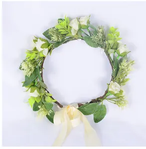 Détail d'une couronne de roses blanches avec feuilles vertes et nœud en ruban crème